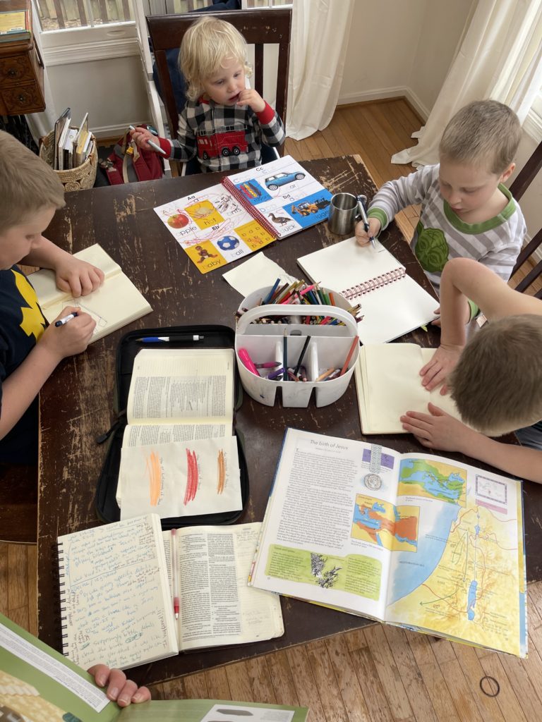 Kids at a table with books and pencils doing Bible study